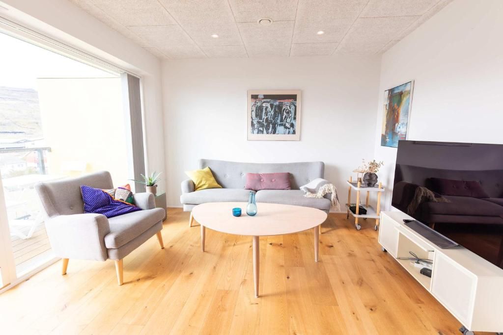 Ein modernes Wohnzimmer mit einer Couch, einem Sessel, einem Couchtisch und einer TV-Konsole.