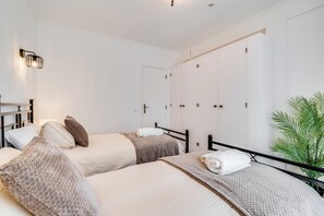 Une chambre d’hôtel avec deux lits, une armoire, une plante et un luminaire au plafond.
