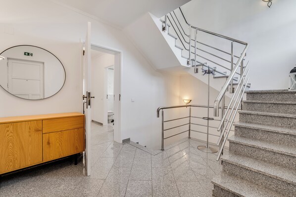 Un intérieur moderne avec un banc en bois, une porte blanche et un escalier doté de rampes en métal.