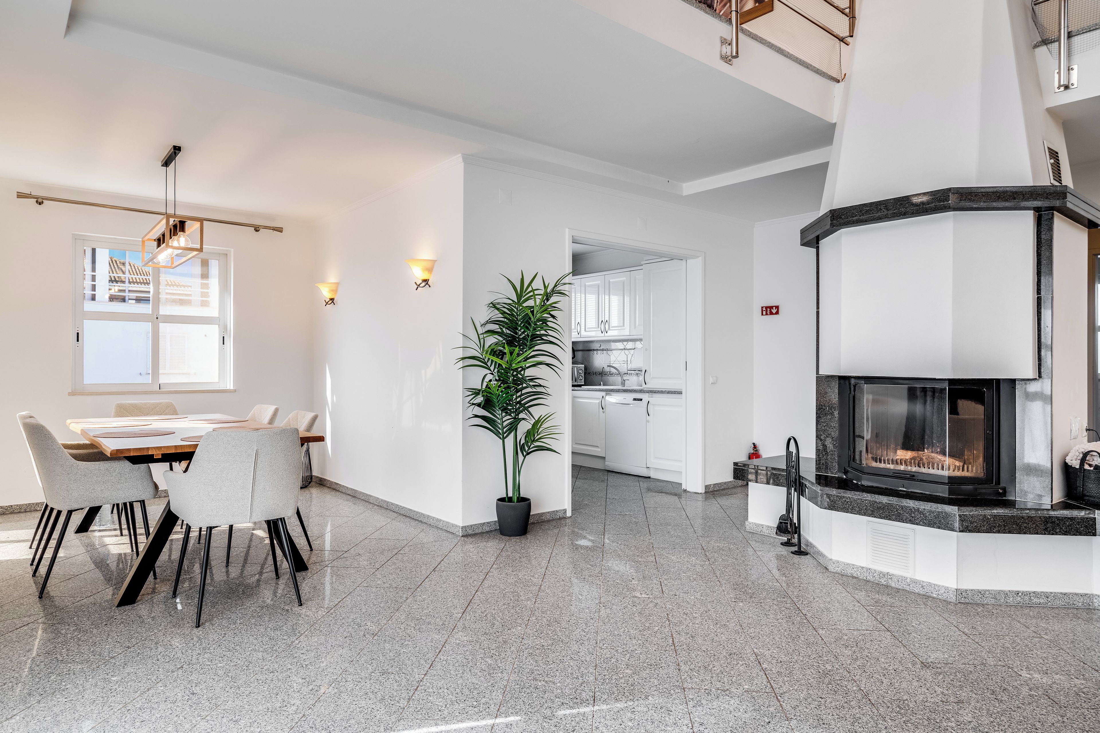 Un interior modern amb zona de menjador, cuina i llar de foc.