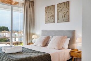 Une chambre d’hôtel comprenant un lit, deux oreillers, une table de chevet avec une lampe et deux œuvres d’art murales.