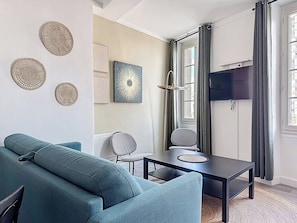 A modern living room with a sofa, a table, and a TV mounted on the wall. - Apartment for 6 people near the sea in Toulon (Toulon)
