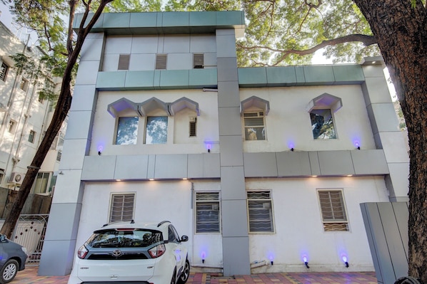 A multi-story building with a car parked in front. - Super Collection O Sunshine Near Inox (Pune)