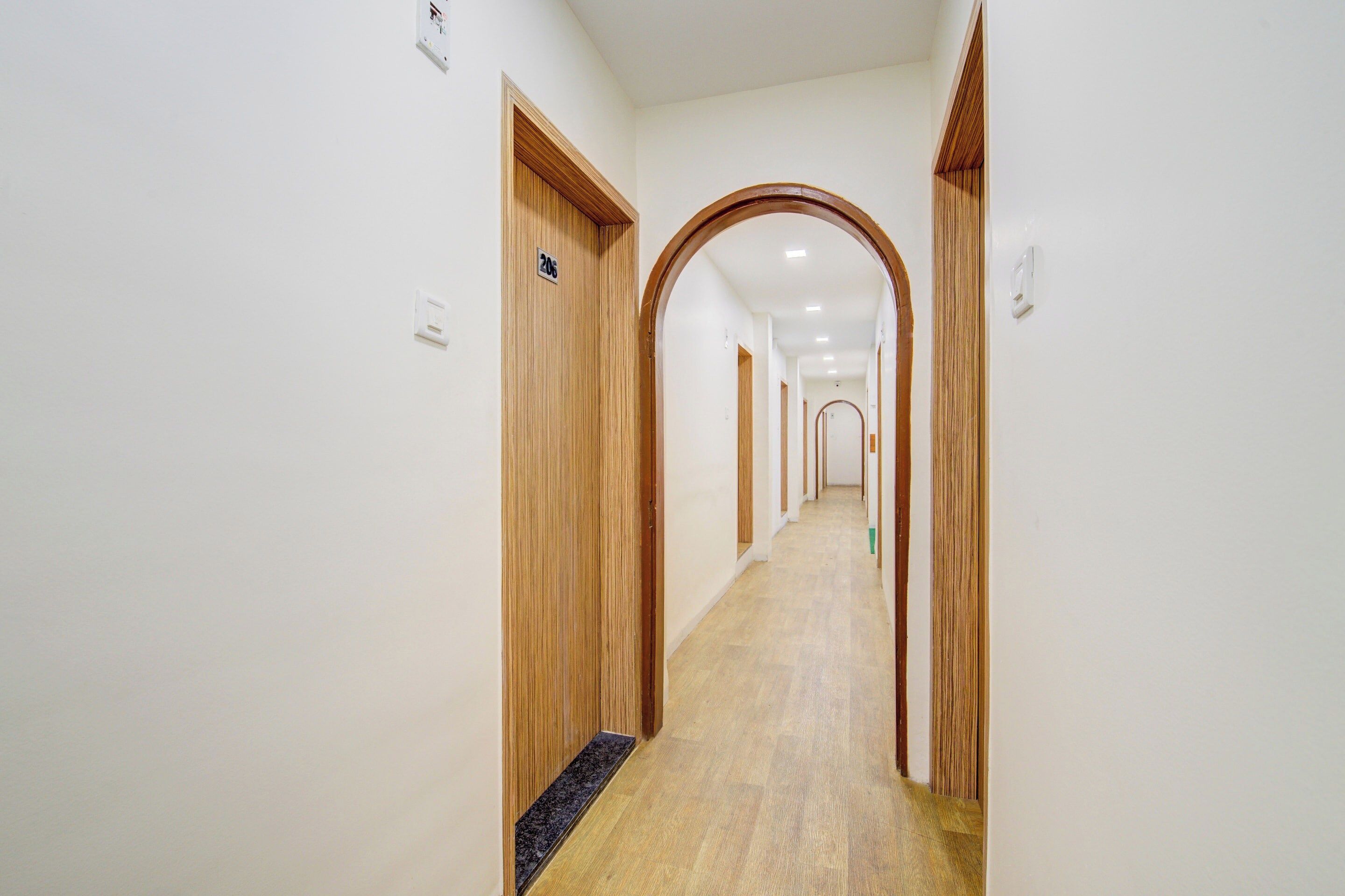 Un couloir avec des portes en bois, un sol recouvert de moquette et un plafond doté d’un éclairage encastré.