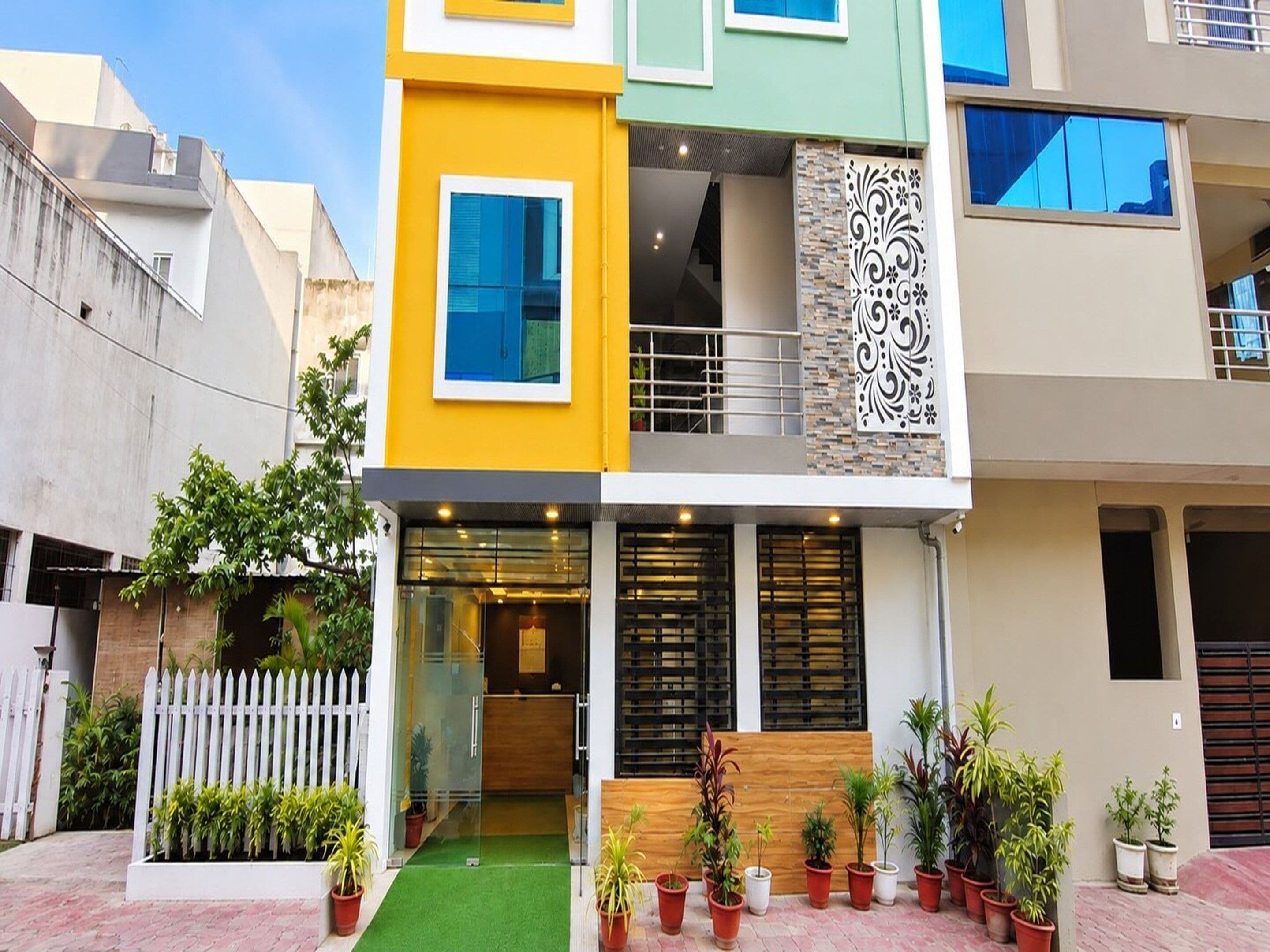 A two-story building with a reception area, potted plants, and a white picket fence.