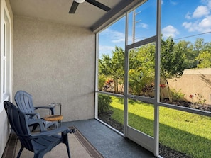 A covered patio with a ceiling fan, a chair, and a small table. - Resort-Style Naples Escape | Arboretum Pool & Spa | Near Downtown (Naples)