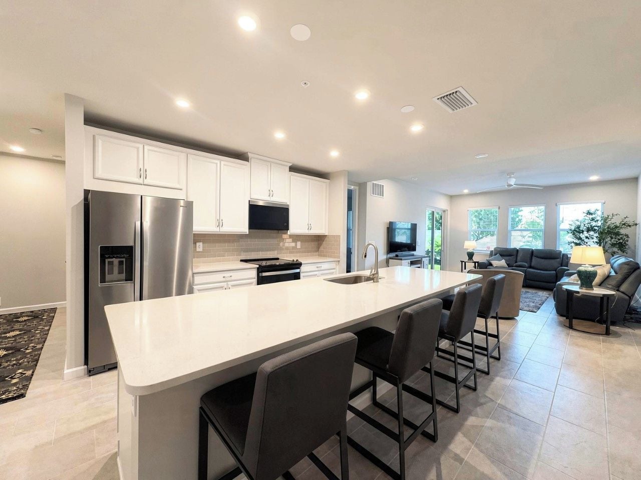 A modern kitchen with a large island, stainless steel appliances, and a dining area with bar stools.