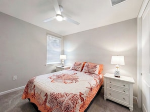 A bedroom with a bed, nightstands, a ceiling fan, and a window with blinds. - Resort-Style Naples Escape | Arboretum Pool & Spa | Near Downtown (Naples)