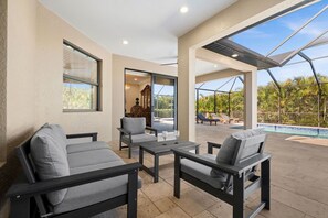 An outdoor patio with seating, a pool, and a view of the surrounding landscape. - Coral Breeze Retreat (Cape Coral)