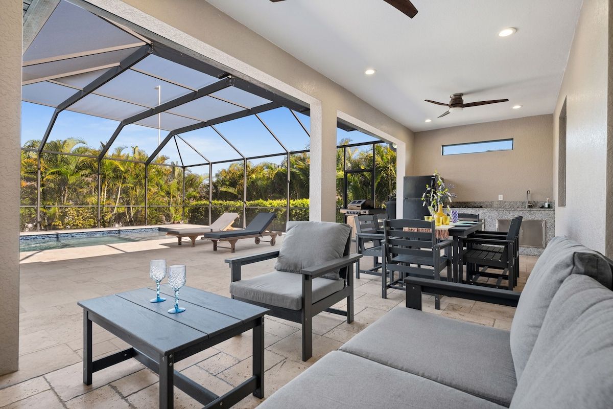 A spacious outdoor patio with a pool, seating area, and a kitchen.