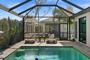 A covered outdoor swimming pool with lounge chairs and a glass enclosure. - Terra Cove | Heated Pool, Dock & Gulf Access (Cape Coral)