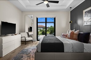 Een moderne slaapkamer met een bed, een televisie, een bureau en een stoel.