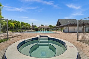 En swimmingpool med dybdemarkering på 97 centimeter, omgivet af et hegn, med et overdækket siddeområde og en bygning i baggrunden.