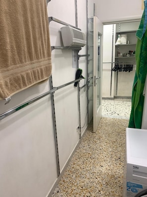 A bathroom with a towel rack, a hairdryer, and a washing machine. - Apartment 'Sul Corso' with balcony, Wi-Fi and air conditioning (Agropoli)