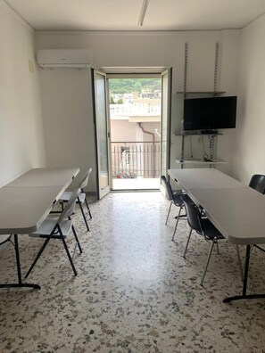 A conference room with a long table, chairs, a television, and a view through an open door to a balcony. - Apartment 'Sul Corso' with balcony, Wi-Fi and air conditioning (Agropoli)