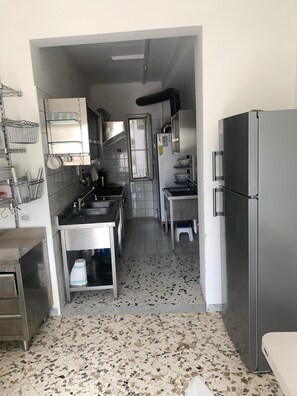 Een keuken met roestvrijstalen apparatuur, een spoelbak en een koelkast.
