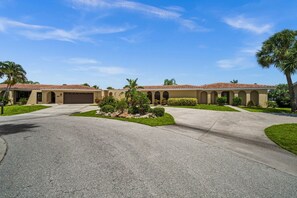 A residential property with a driveway leading to a garage, surrounded by well-maintained landscaping and palm trees. - Punta Gorda Isles| Optional Guest  House (Punta Gorda)