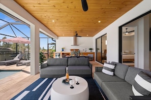 Uma sala de estar moderna com piscina, sofás cinzas e ventoinha de teto.