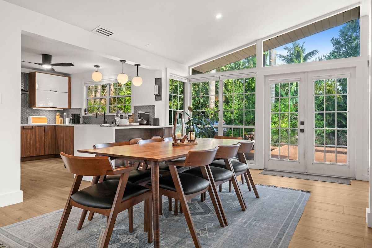 Una cocina moderna con comedor, ventanas amplias y vistas a zonas verdes.