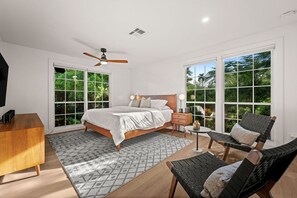 A bedroom with a bed, bedside table, chair, and a ceiling fan. - Serene Escape on McGregor | Fort Myers (Fort Myers)