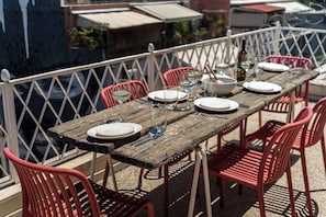 A wooden table set for dining with red chairs, a white railing, and a view of the sea. - Psyrri Home, Acropolis View and Lycabettus Terrace (Athens)