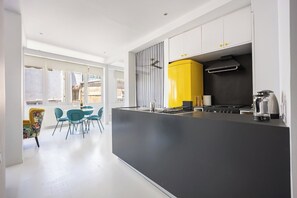 A modern kitchen with a central island, a yellow appliance, and a dining area with blue chairs. - Psyrri Home, Acropolis View and Lycabettus Terrace (Athens)