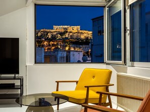A room with a view of the Acropolis at sunset, a yellow armchair, a glass table, and a black TV stand. - Psyrri Home, Acropolis View and Lycabettus Terrace (Athens)