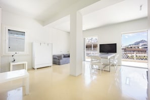 A spacious room with a large window, a flat-screen TV, a white desk, a grey sofa, and a white wardrobe. - Psyrri Home, Acropolis View and Lycabettus Terrace (Athens)