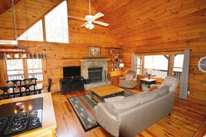 Un interior de cabaña acogedor con chimenea, muebles de madera y una televisión.