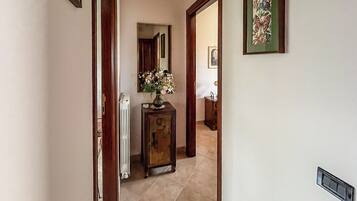 A hallway with a radiator, a wooden cabinet with a vase, and a framed picture on the wall.