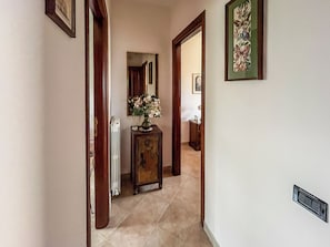 Ein Flur mit einem Heizkörper, einer Holzkabine mit einer Vase und einem gerahmten Bild an der Wand.