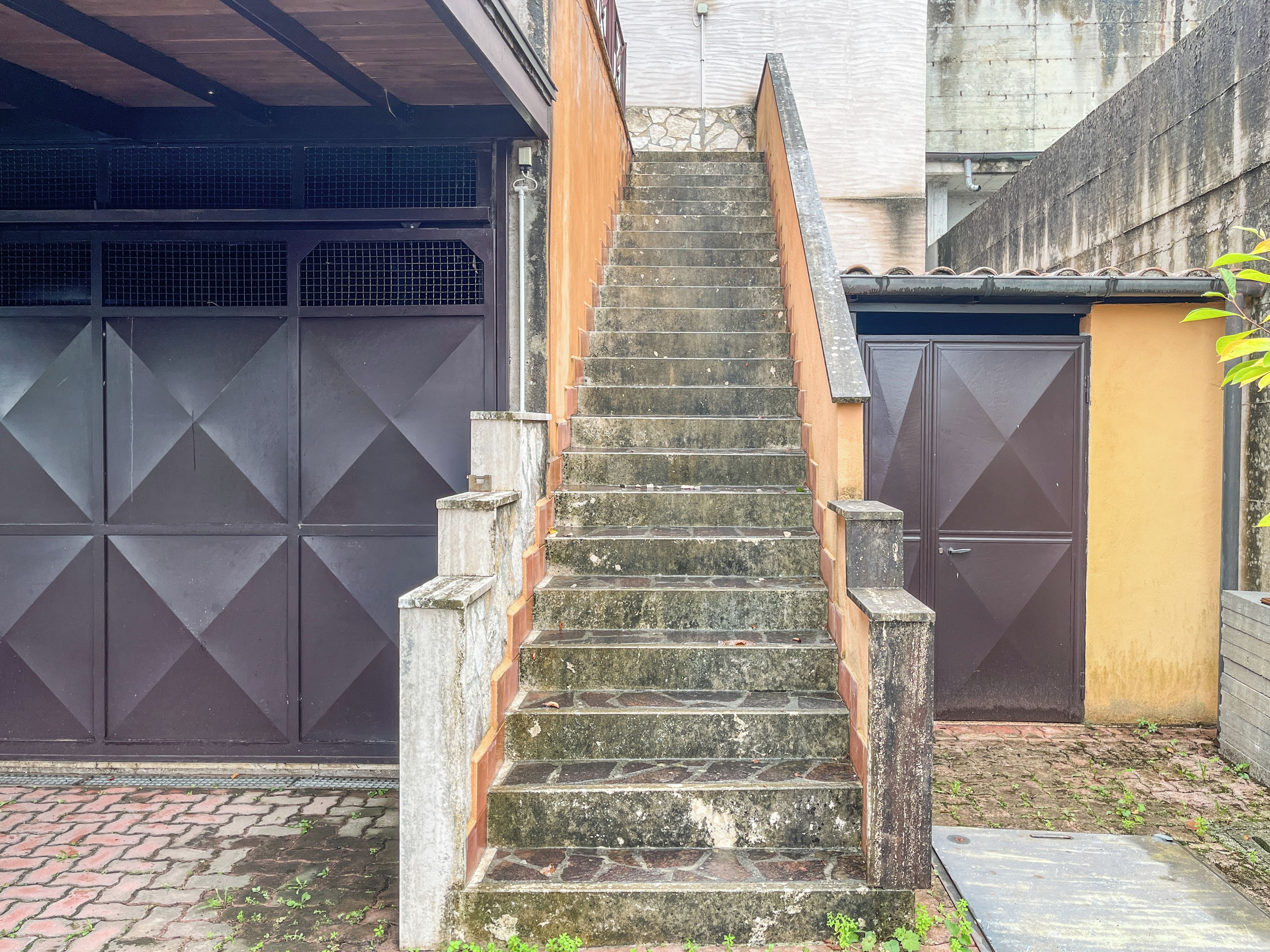 Un escalier extérieur en pierre menant à une entrée fermée par un portail.