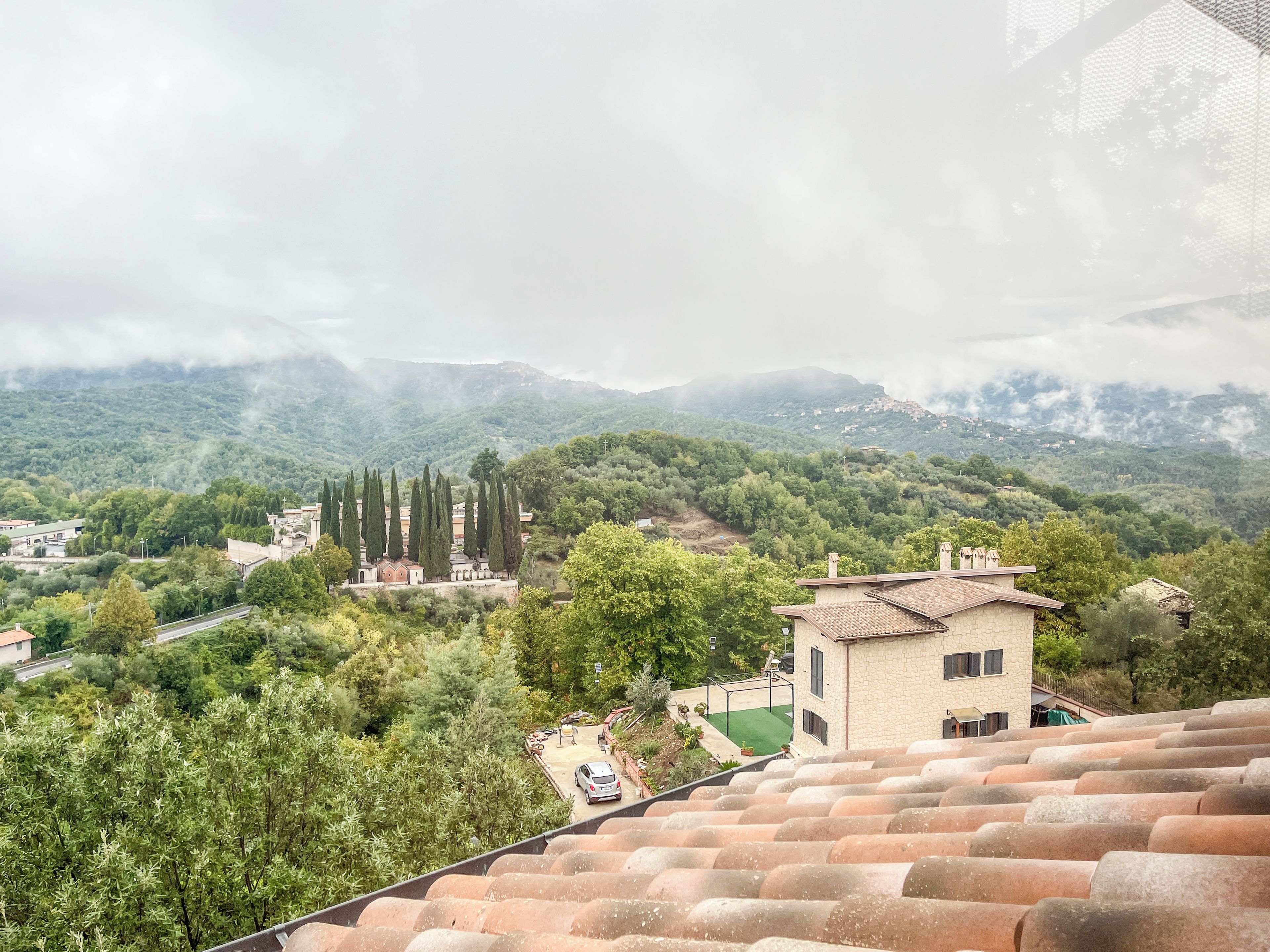 Un quartier résidentiel situé sur une colline, avec des maisons à étages, une église et une vue sur les collines environnantes.