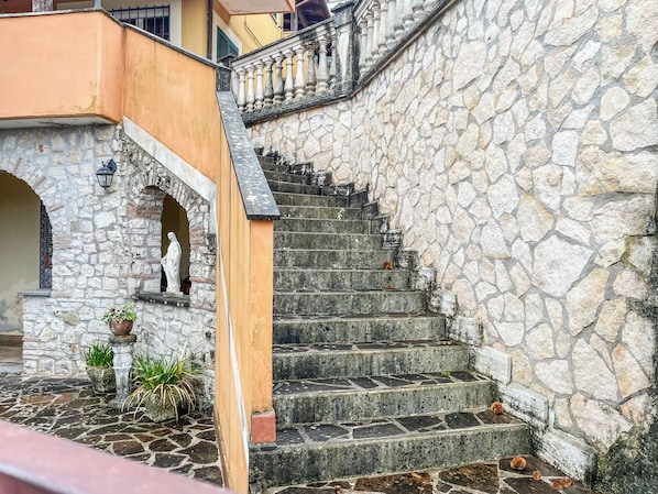 A stone staircase leading to a building entrance with a statue and potted plants. - Casa Censi F1 (Rocca Santo Stefano)
