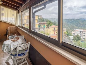 Un balcón con mesa y sillas, con vistas a una zona residencial con edificios y colinas.