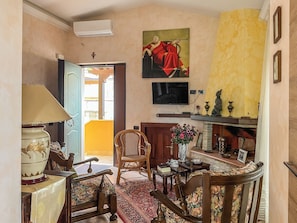 A room with a bed, a chair, a table, a lamp, a television, a painting, and a fireplace. - Casa Censi F1 (Rocca Santo Stefano)