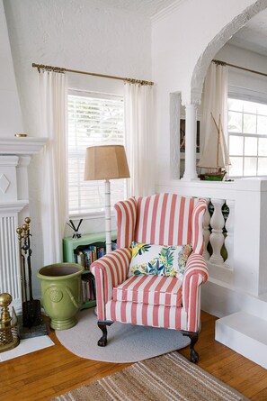 A room with a striped armchair, a green pot, a lamp, and a bookshelf. - Palm Beach Chic Pink Bungalow: King Bed (West Palm Beach)