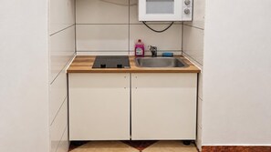 A compact kitchen with a microwave, a sink, and a countertop. - Stay Longer 1BR near Westbahnhof (Vienna)