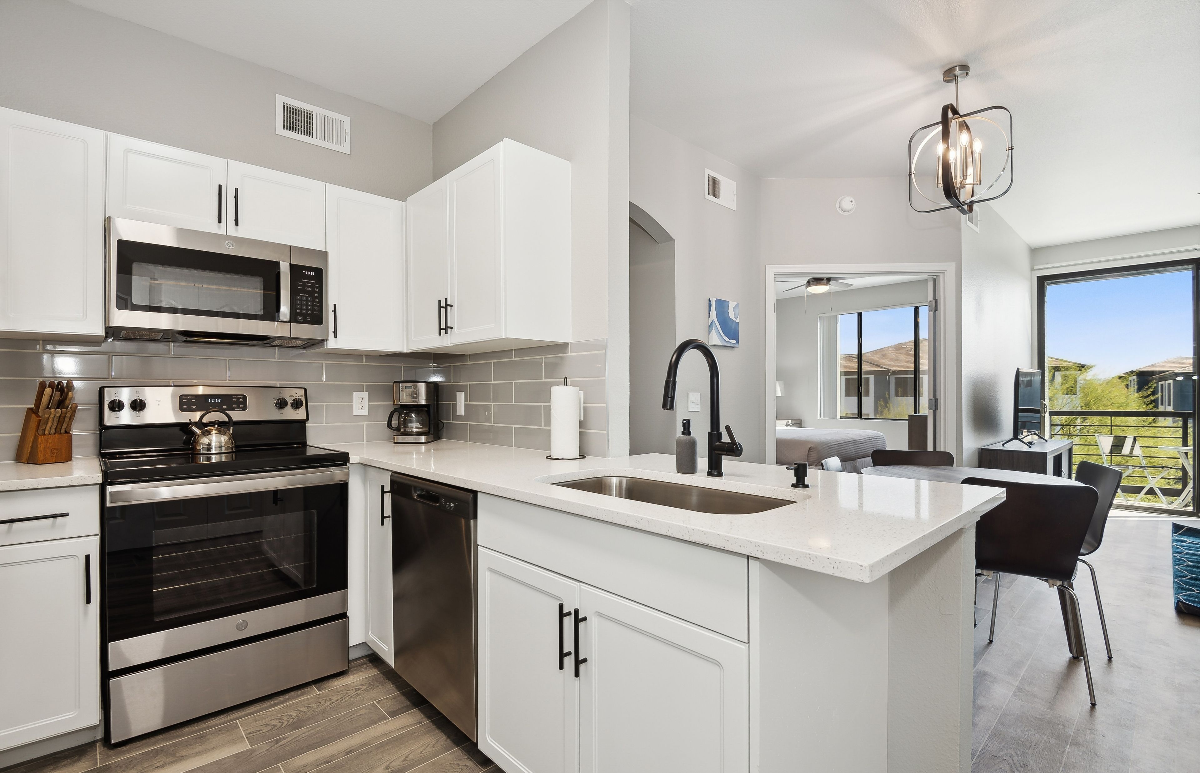 A modern kitchen with white cabinetry, stainless steel appliances, and a large island with a sink.