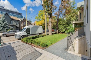 Une rue résidentielle où est garé un fourgon blanc sur le bord, avec un vélo et un chemin piétonnier.