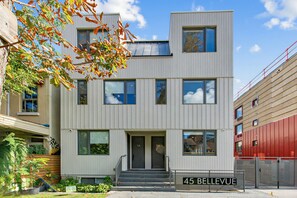 A modern two-story building with a flat roof, large windows, and a sign indicating '45 BELLEVUE.' - 
Furnished 2 Bedroom Townhouse in Kensington Market (Toronto)