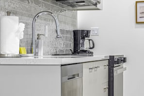 A modern kitchen with a stainless steel faucet, a coffee maker, and a dishwasher. - 
Furnished 2 Bedroom Townhouse in Kensington Market (Toronto)