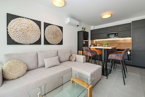 A modern living room with a grey sofa, a glass coffee table, and two large abstract wall art pieces. - Apartment Smash with Private pool (Novalja)