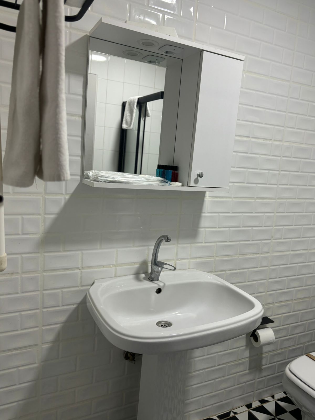 Un baño con lavamanos blanco, un espejo encima y un inodoro.