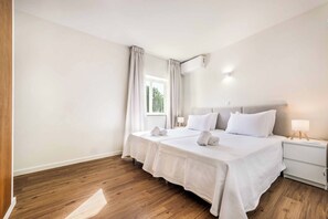 A hotel room with a large bed, a bedside table, a nightstand, and a window with curtains. - Villa Gardenia Vista (Albufeira)