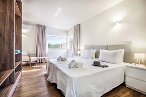 A hotel room with a large bed, a bedside table, a chair, and a wardrobe. - Villa Gardenia Vista (Albufeira)