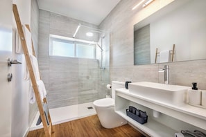 A modern bathroom with a glass-enclosed shower, a white toilet, and a vanity with a mirror. - Villa Gardenia Vista (Albufeira)