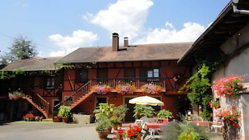 A traditional building with a balcony, outdoor seating, and potted plants.