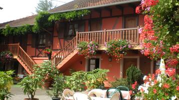A traditional building with a staircase, potted plants, and outdoor seating.