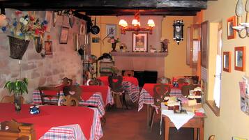 Un restaurant avec de nombreuses tables recouvertes de nappes à carreaux rouges et blancs, des chaises en bois et une variété de décorations murales, notamment des tableaux encadrés et une horloge.